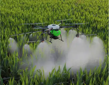 Agricultural drone spraying crops in a green field with visible mist.