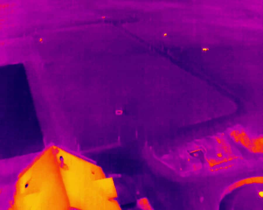 Four farmers in a lush field observing a drone spraying crops, using digital devices to analyze agricultural data.